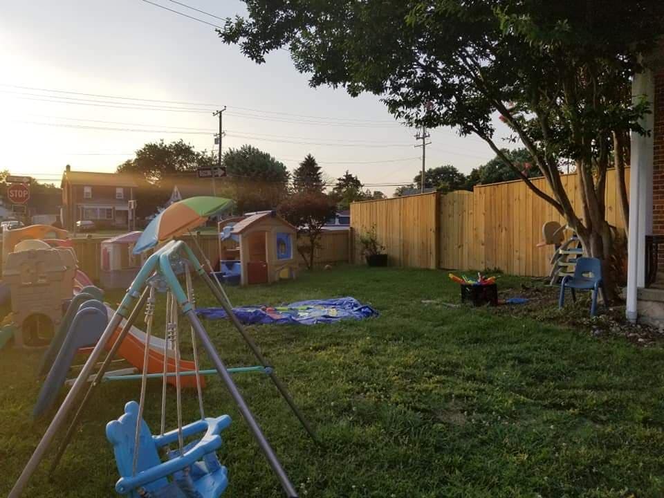 Backyard with a swing set, playhouse, and wooden fence