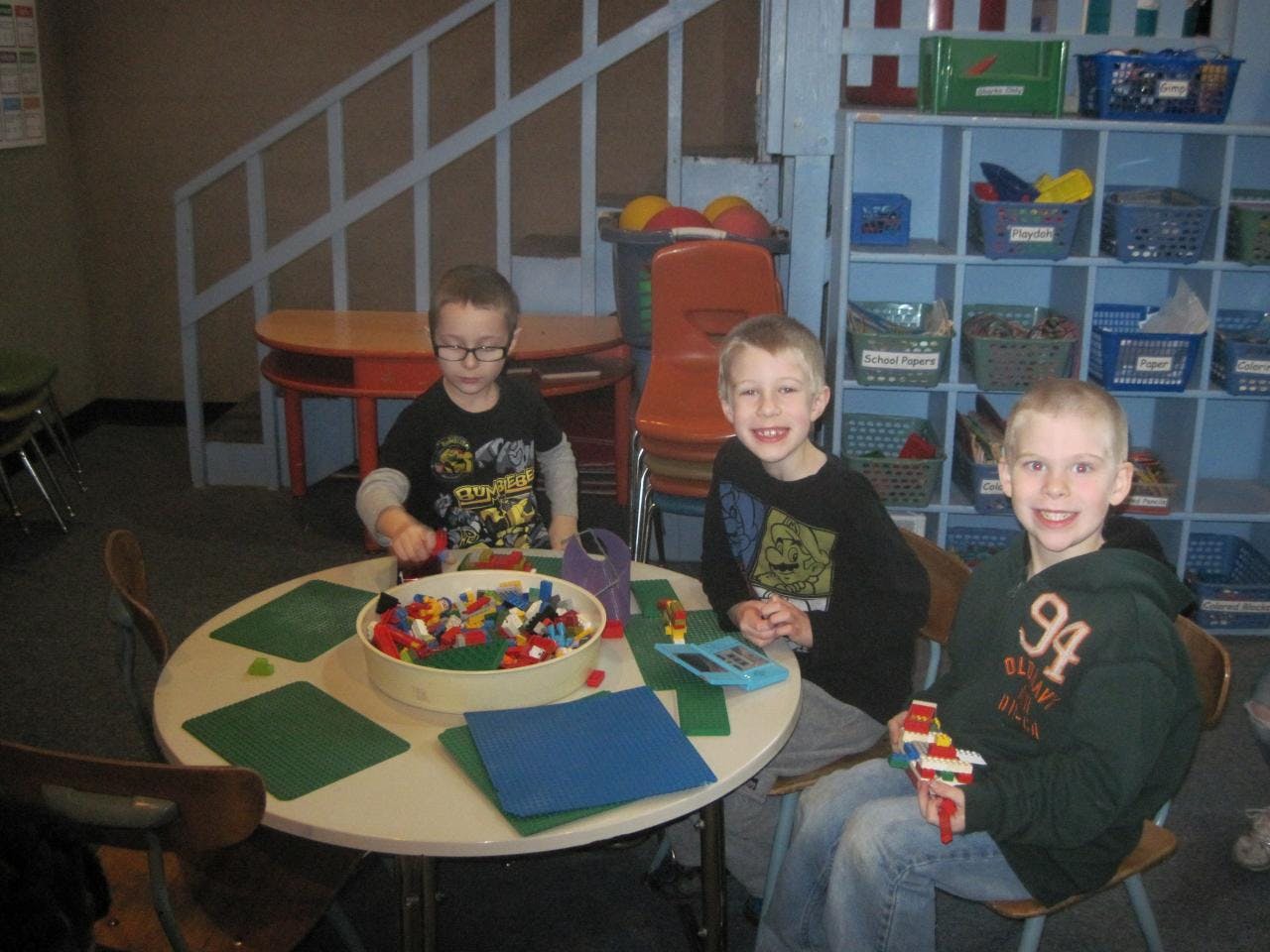 Three children sitting at a table with building blocks