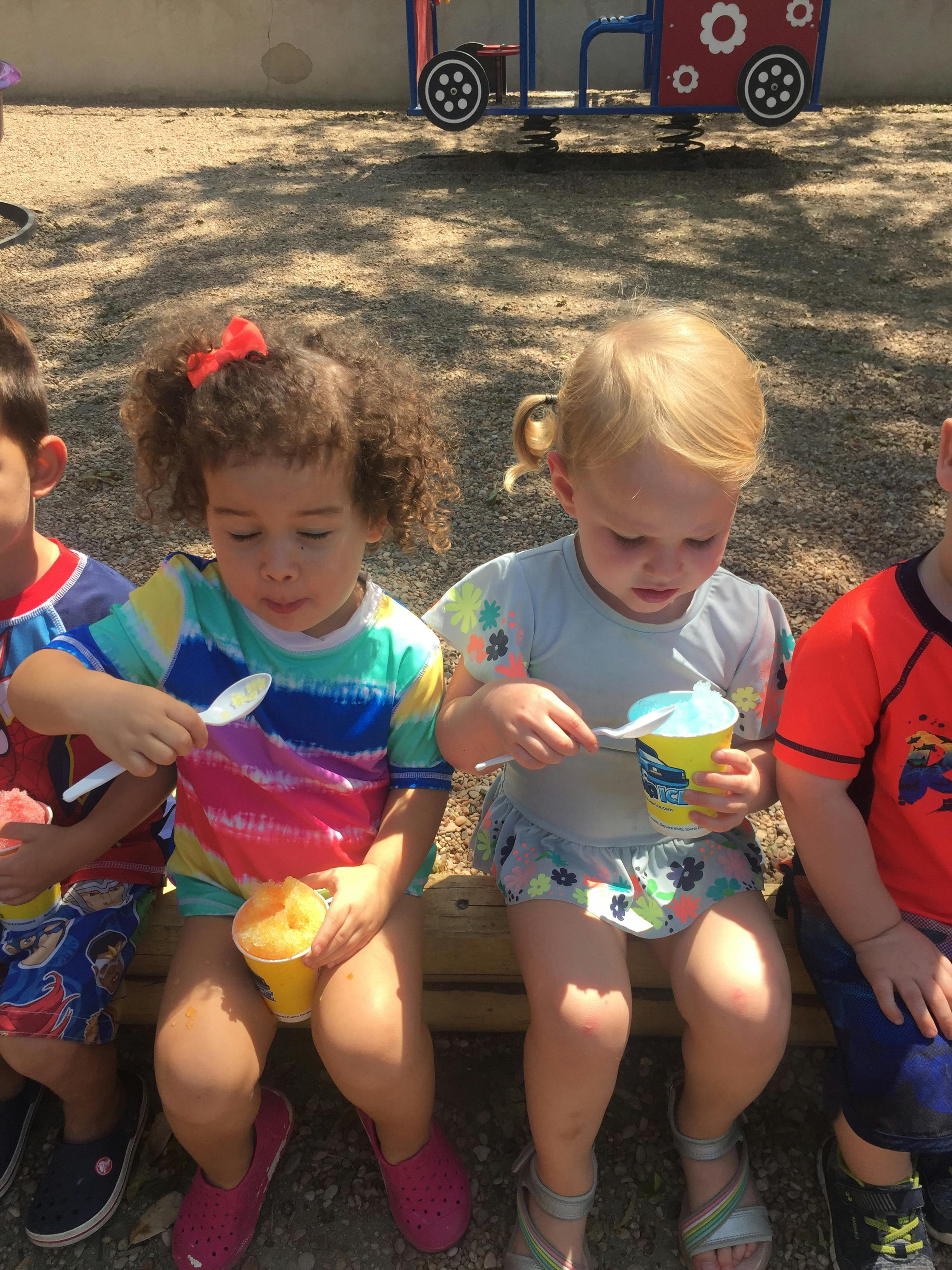 Two children eating frozen treats with spoons