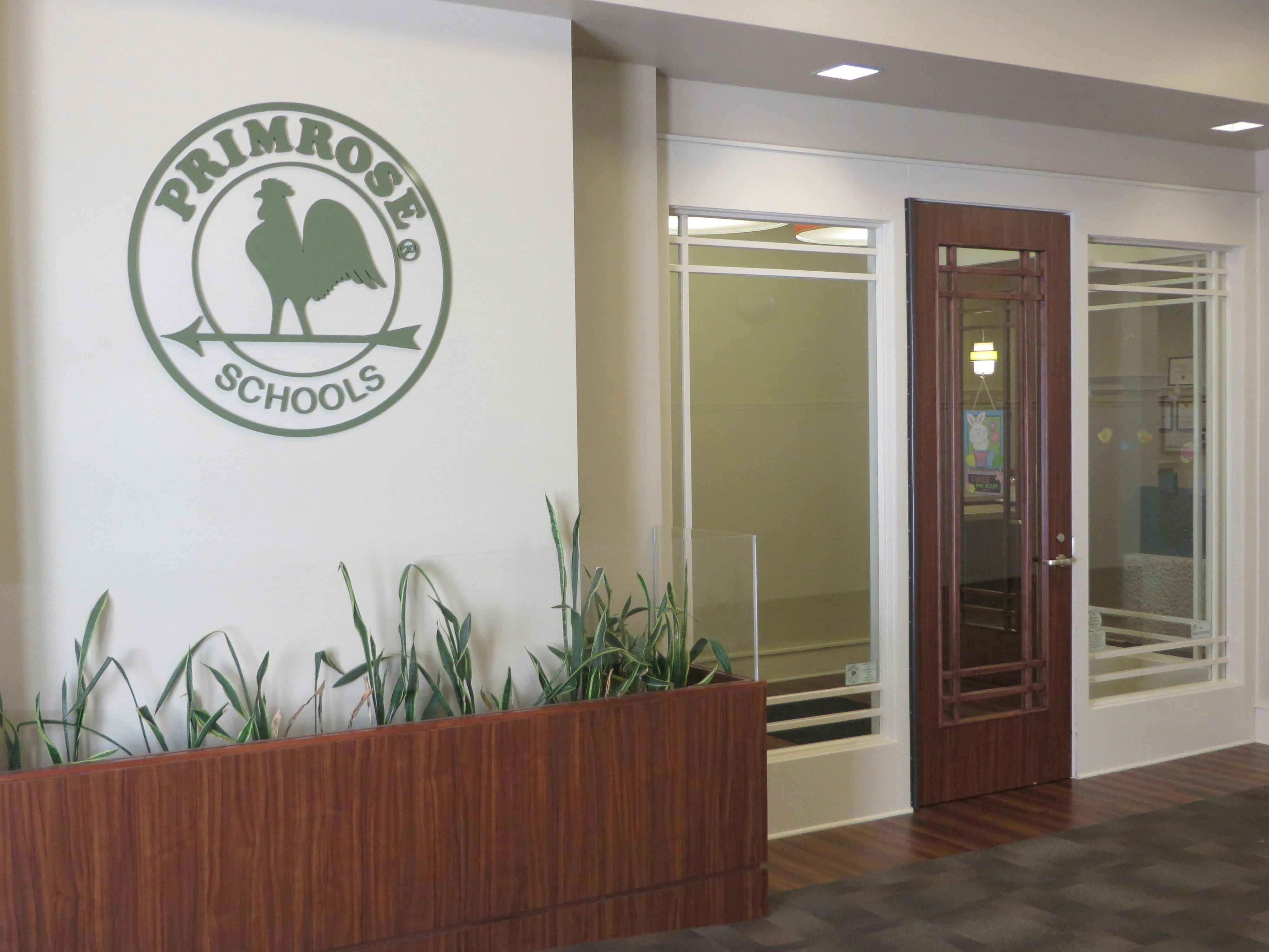 Primrose Schools logo on a wall next to a door and windows