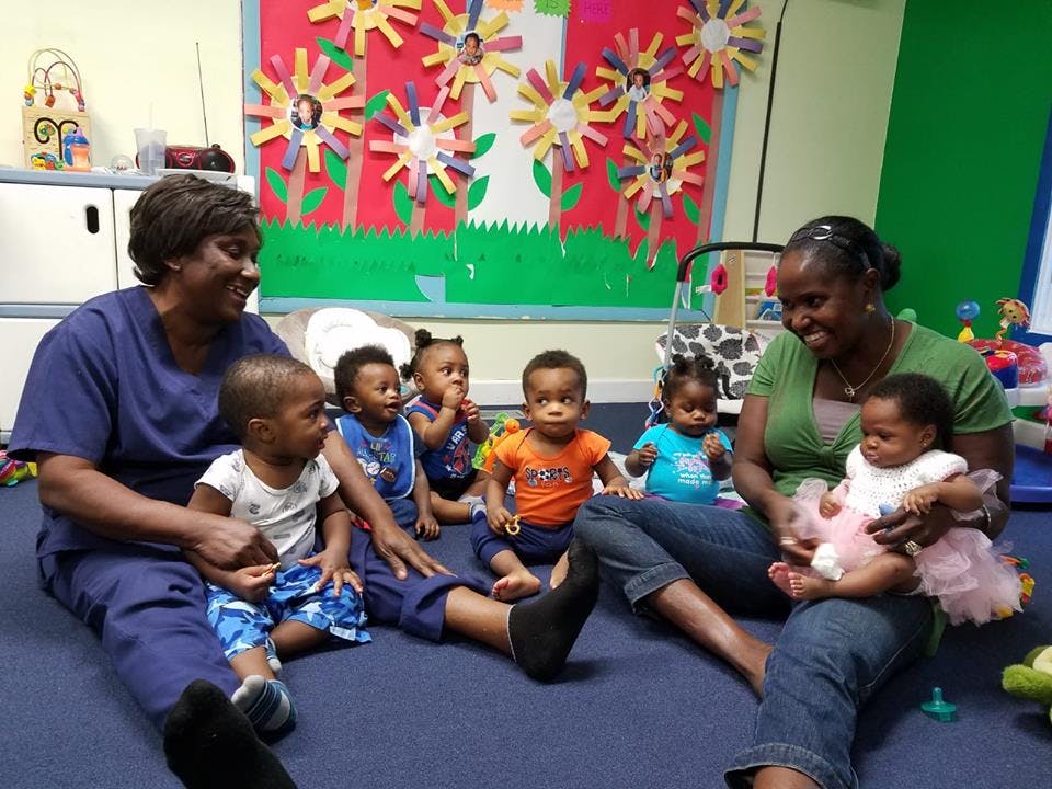 Two people sitting on the floor with multiple babies and children