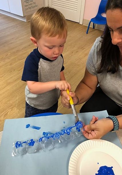 Child and person painting with blue paint