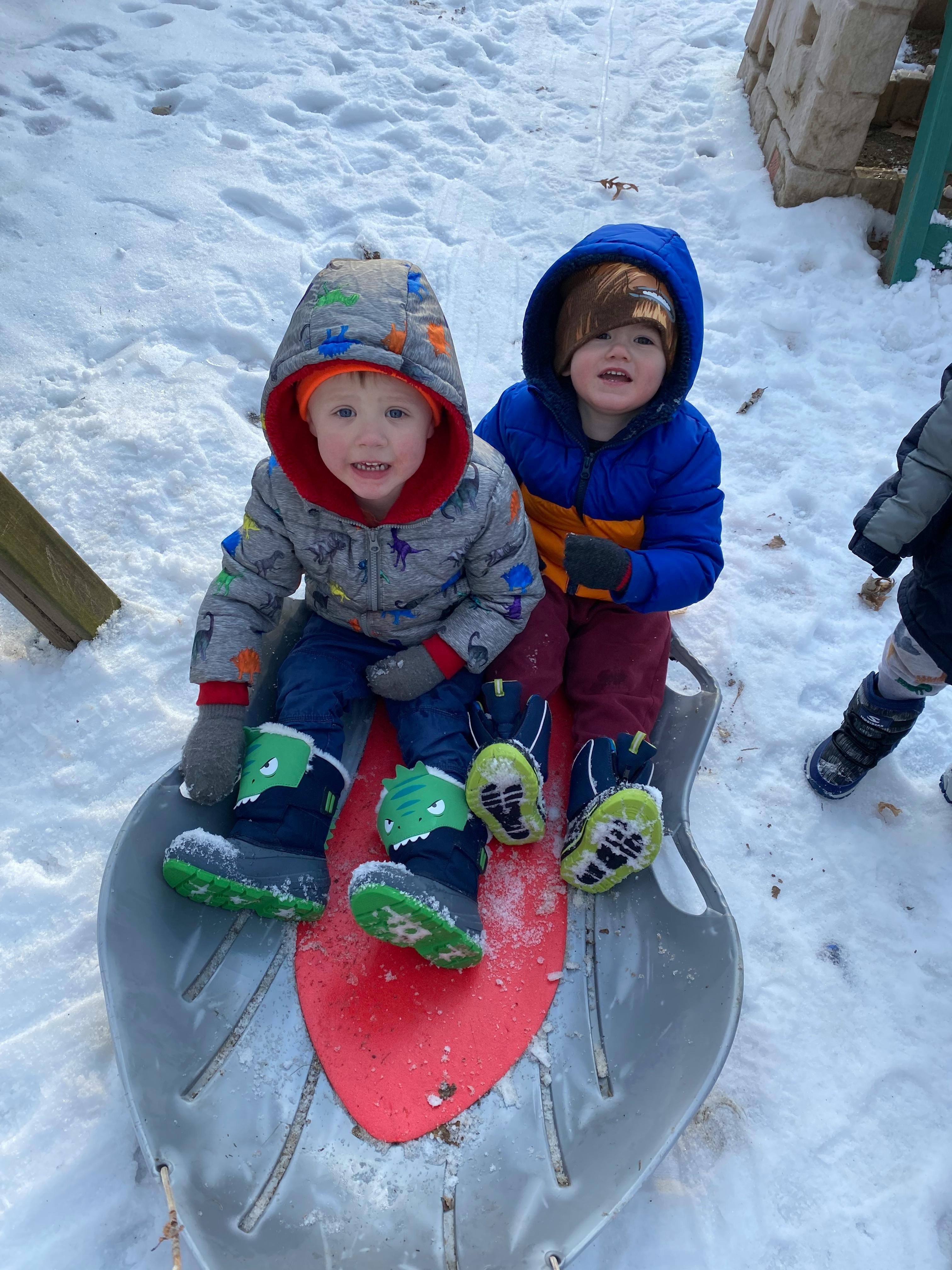 Two children sitting on a sled in the snow