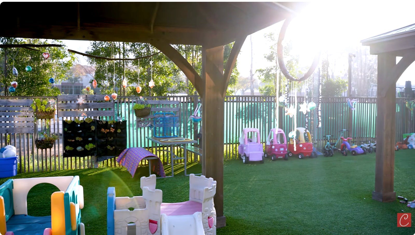 Outdoor play area with green turf, child ride-on cars, and hanging decorations