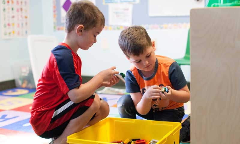 Two children playing with toys in a classroom