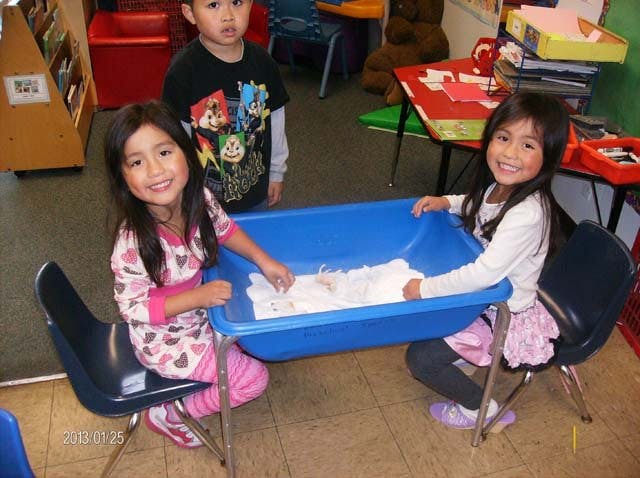 Two children playing with a sensory bin in a classroom