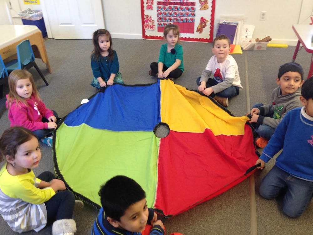 Children sitting around a colorful parachute on the floor