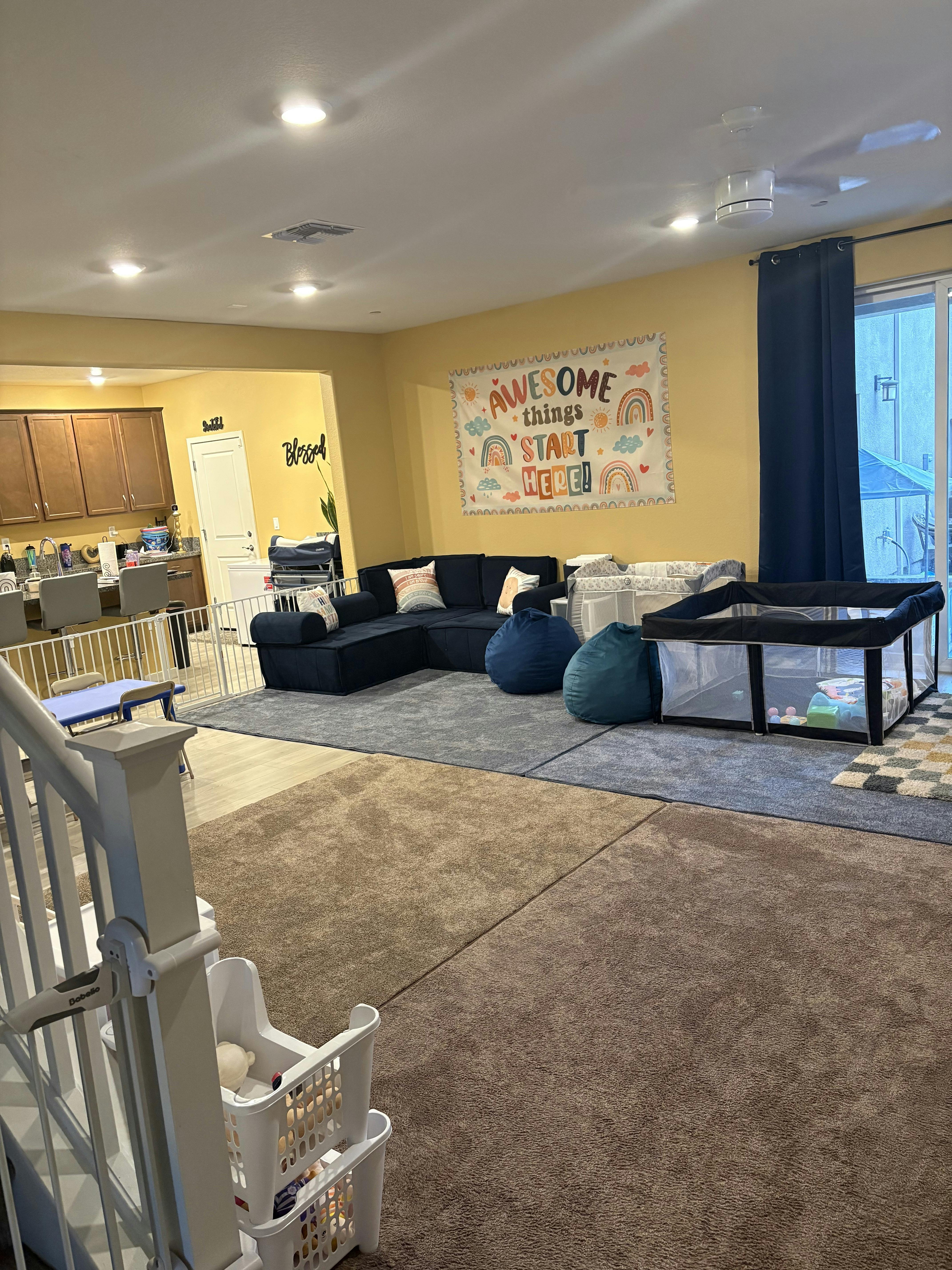 Living room with blue sectional sofa, beanbag chairs, and playpen