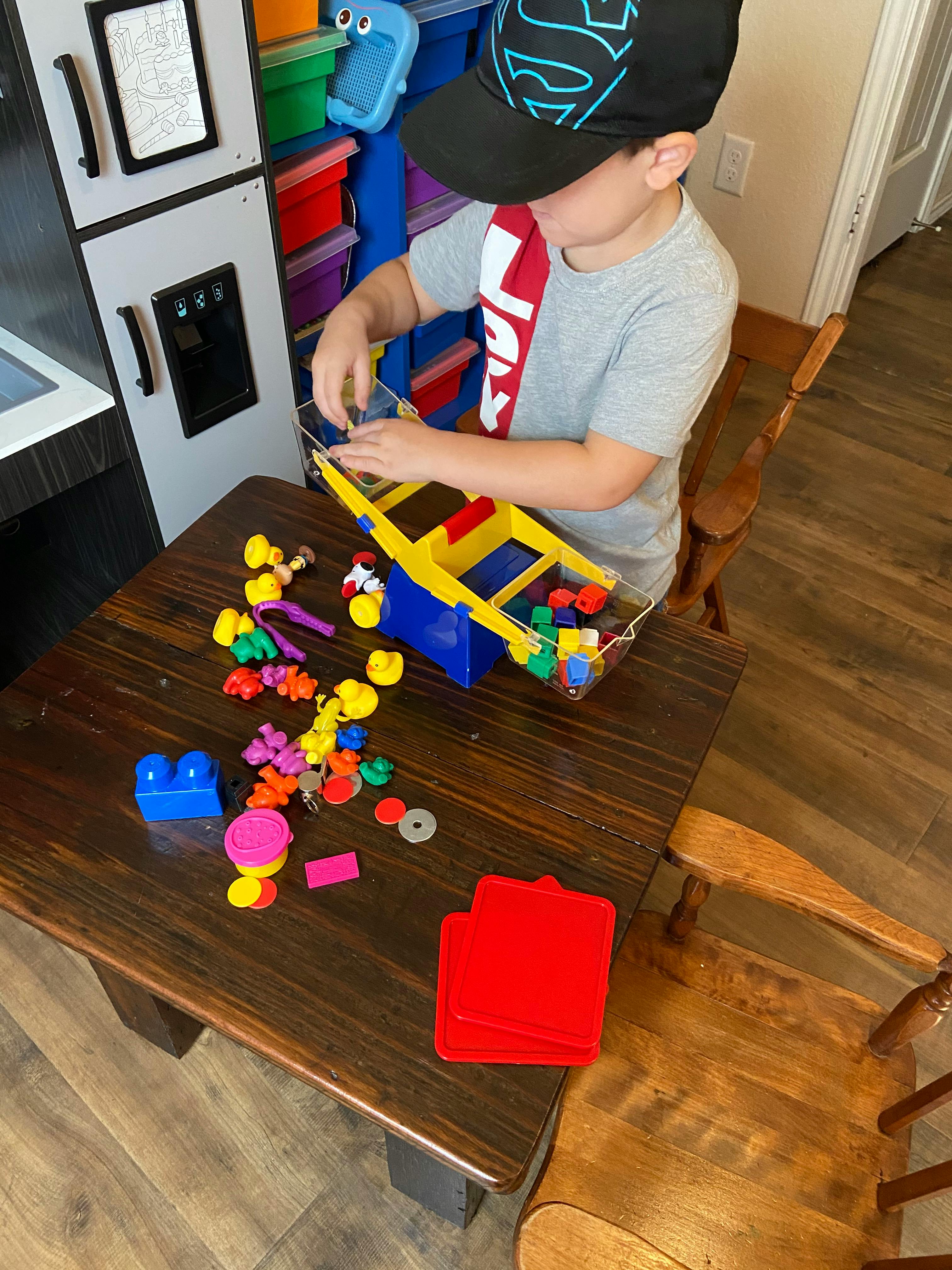 Child playing with colorful building blocks and a toy crane on a wooden table