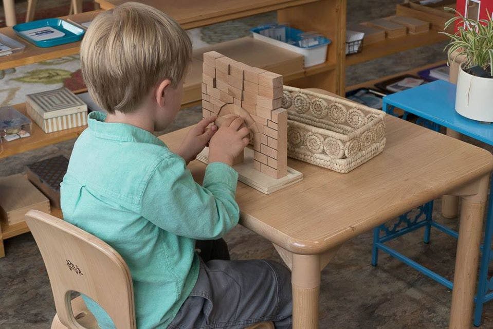 Child sitting at a table, working with a wooden puzzle