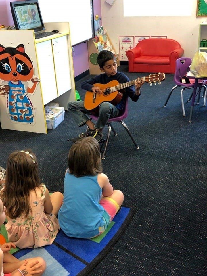 Child playing guitar for other children in a classroom