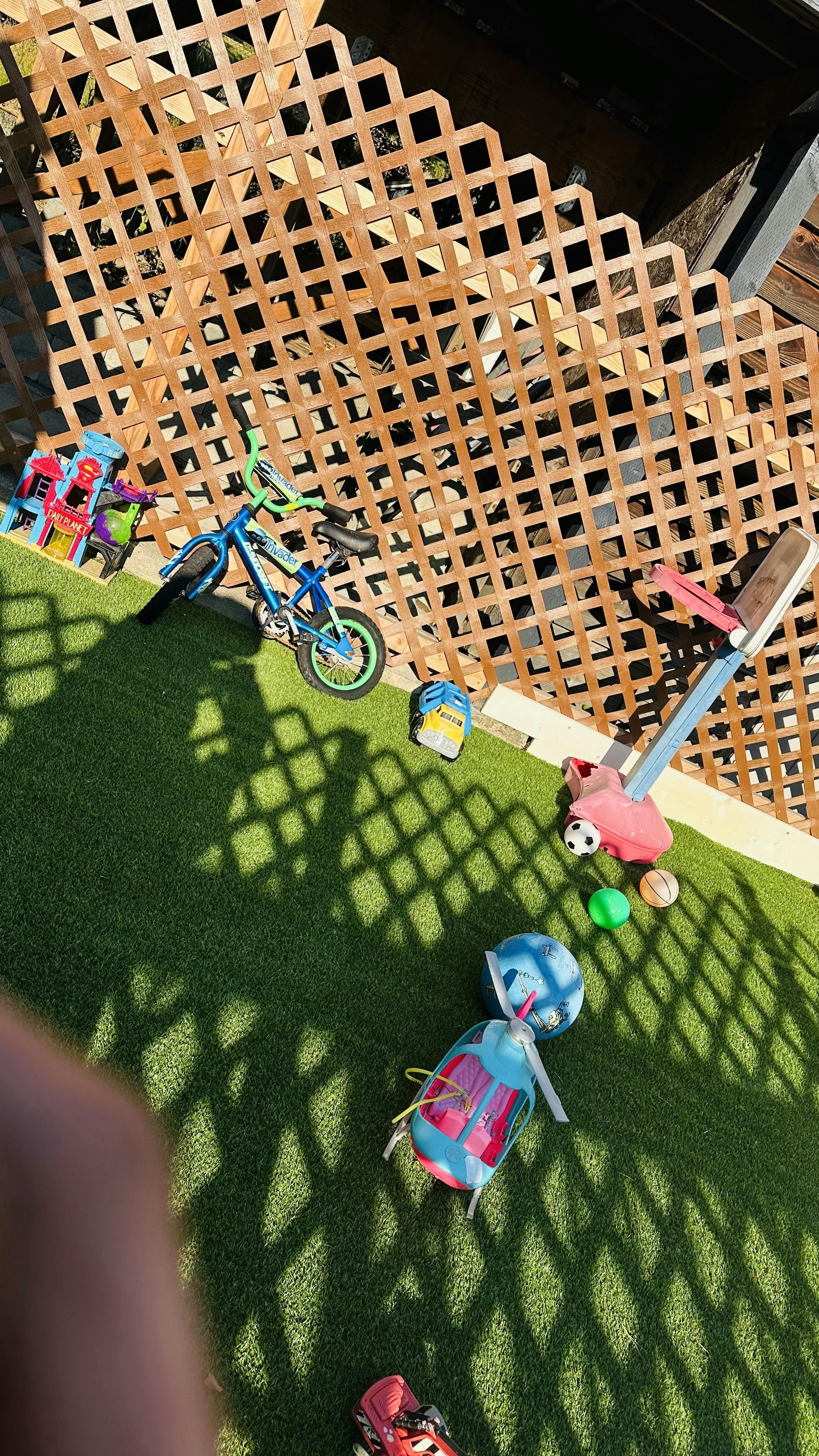 Childrens toys including a bike, basketball hoop, and helicopter on artificial turf