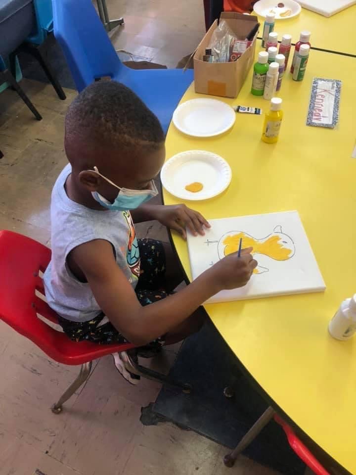 Child in a mask painting on a canvas atable