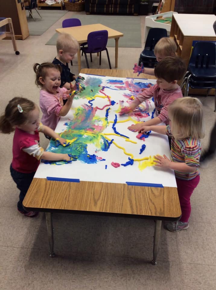 Children finger painting on a large sheet of paper