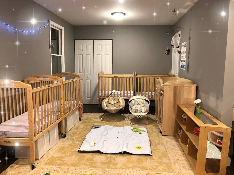 Room with multiple cribs, baby swings, and a play mat on the floor