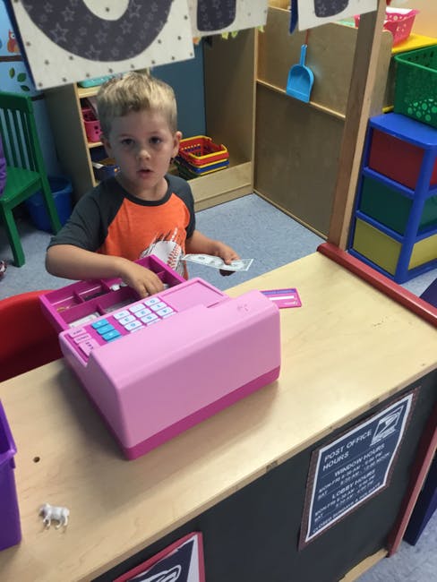 Child playing with a pink toy cash register