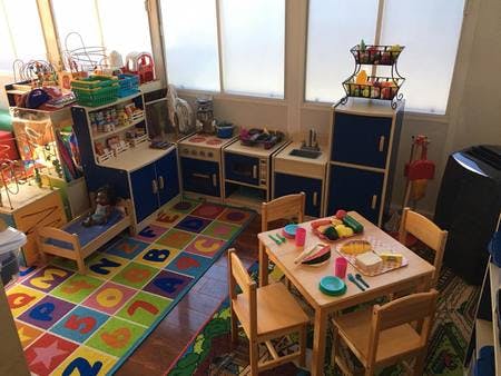 Playroom with toy kitchen, small table and chairs, and alphabet rug