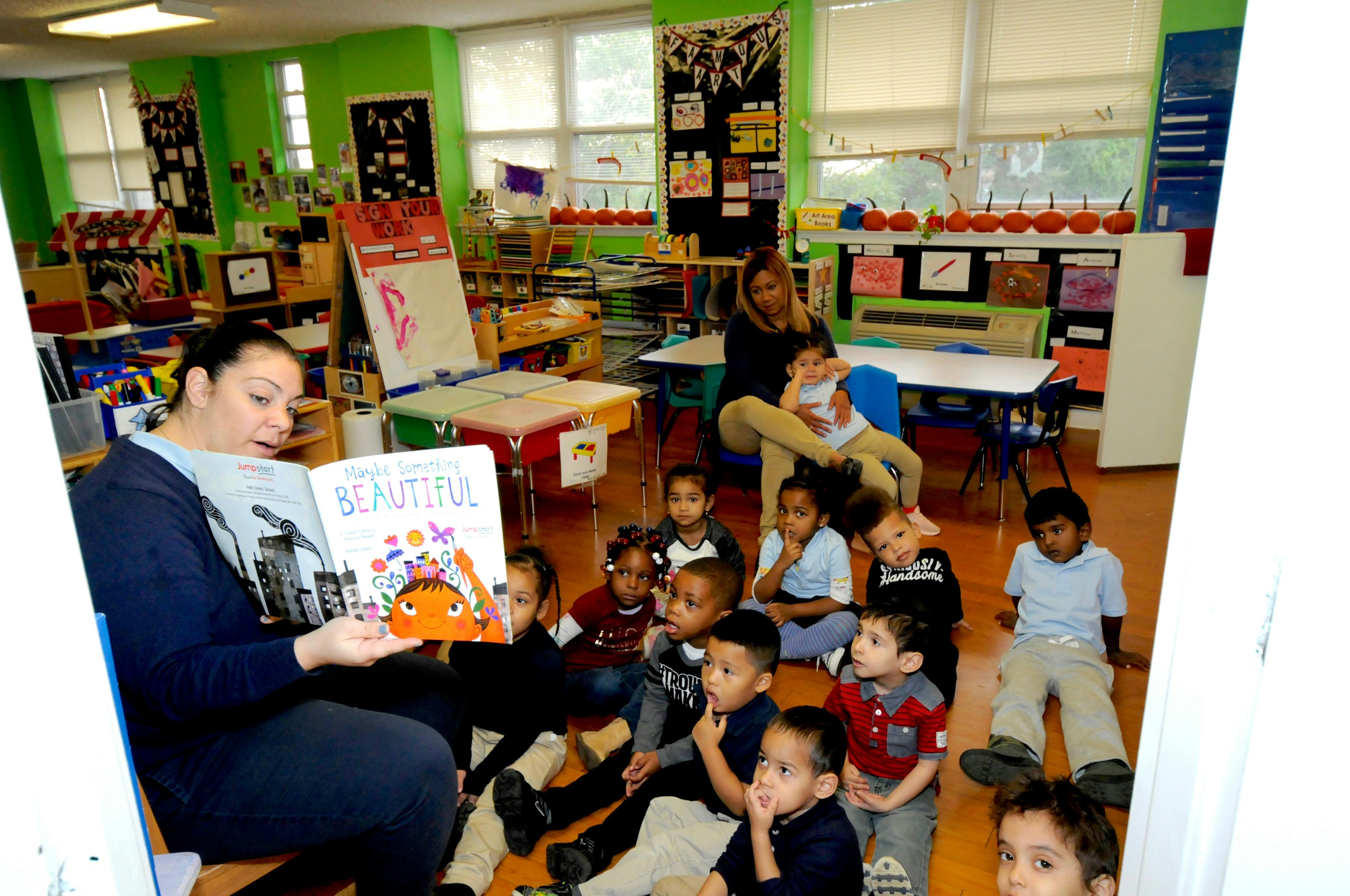 Person reading a book to a group of children in a classroom