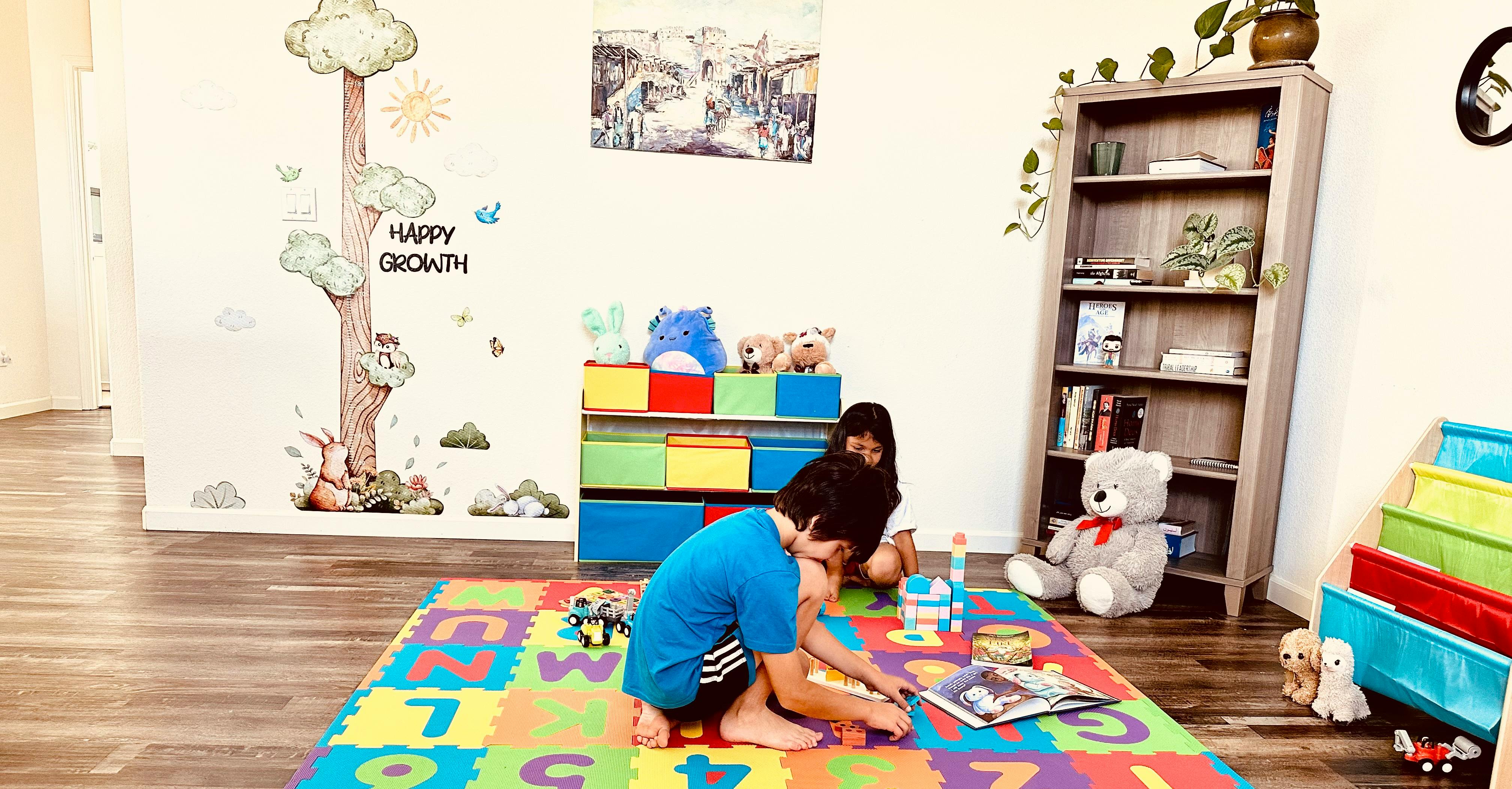Two children playing on a colorful alphabet mat