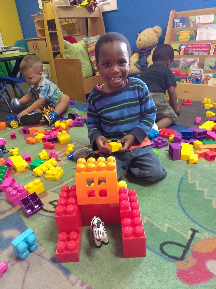 Child playing with building blocks on the floor in a classroom