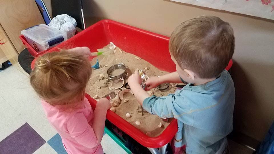 Two children playing in a sand table