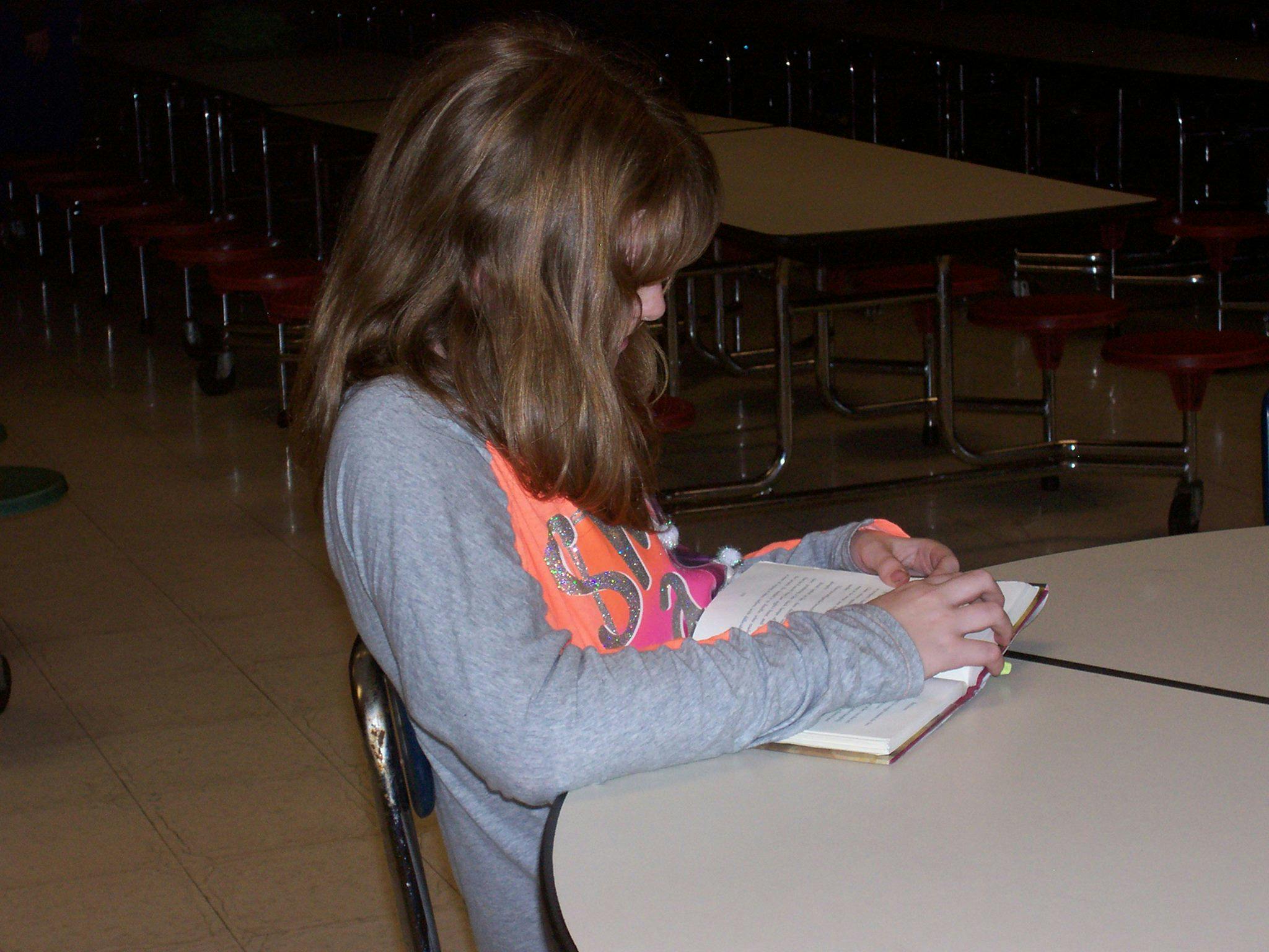 Child sitting at a table reading a book