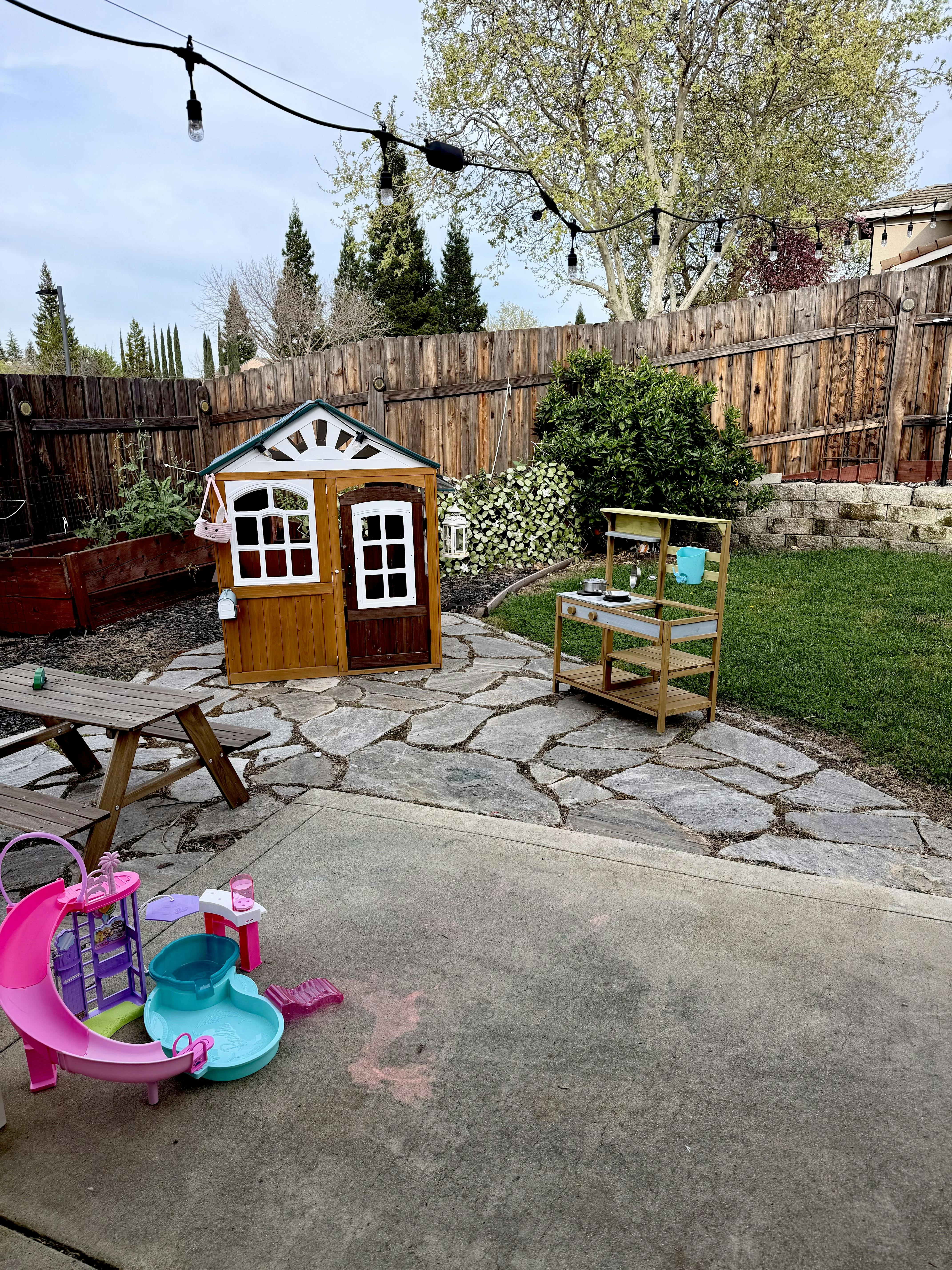 Backyard with playhouse, mud kitchen, picnic table, and doll pool