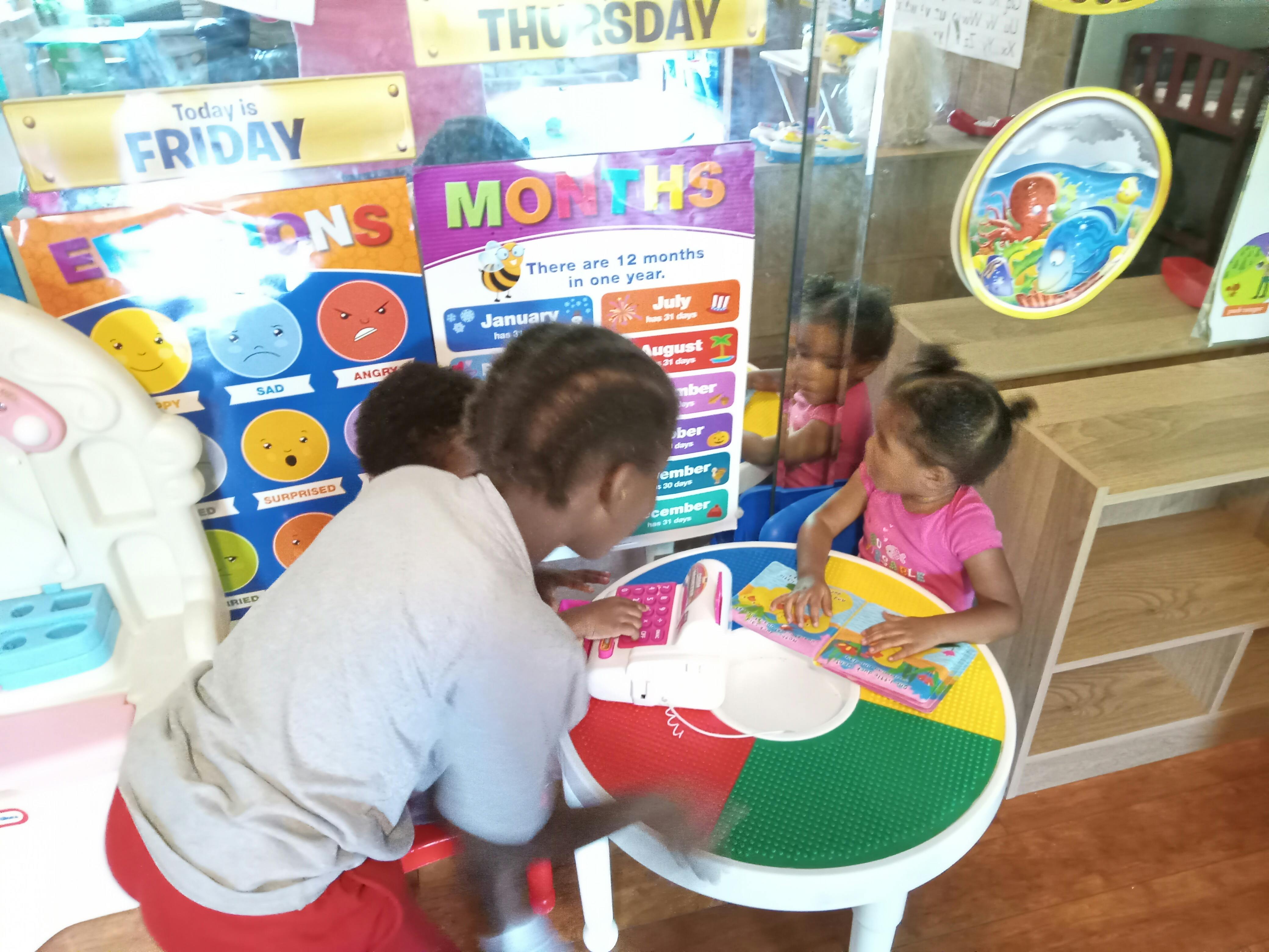 Person interacting with children at a colorful table in a classroom