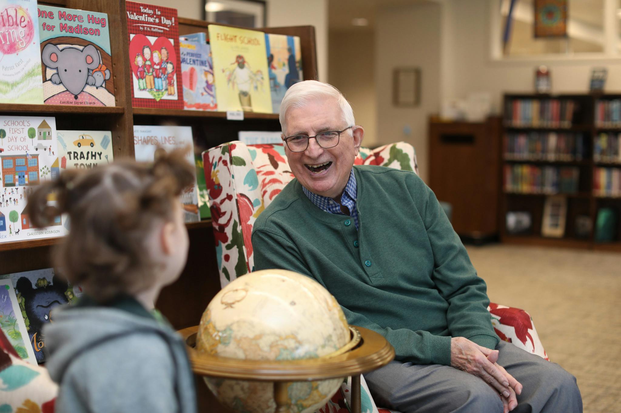 Smiling older person with a child in front of bookshelves