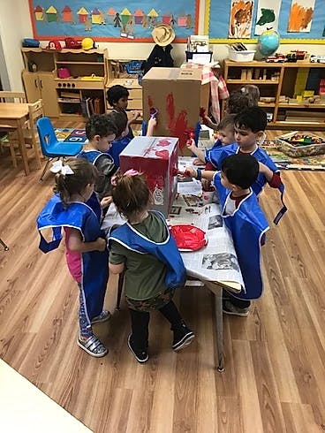 Children painting cardboard boxes in a classroom