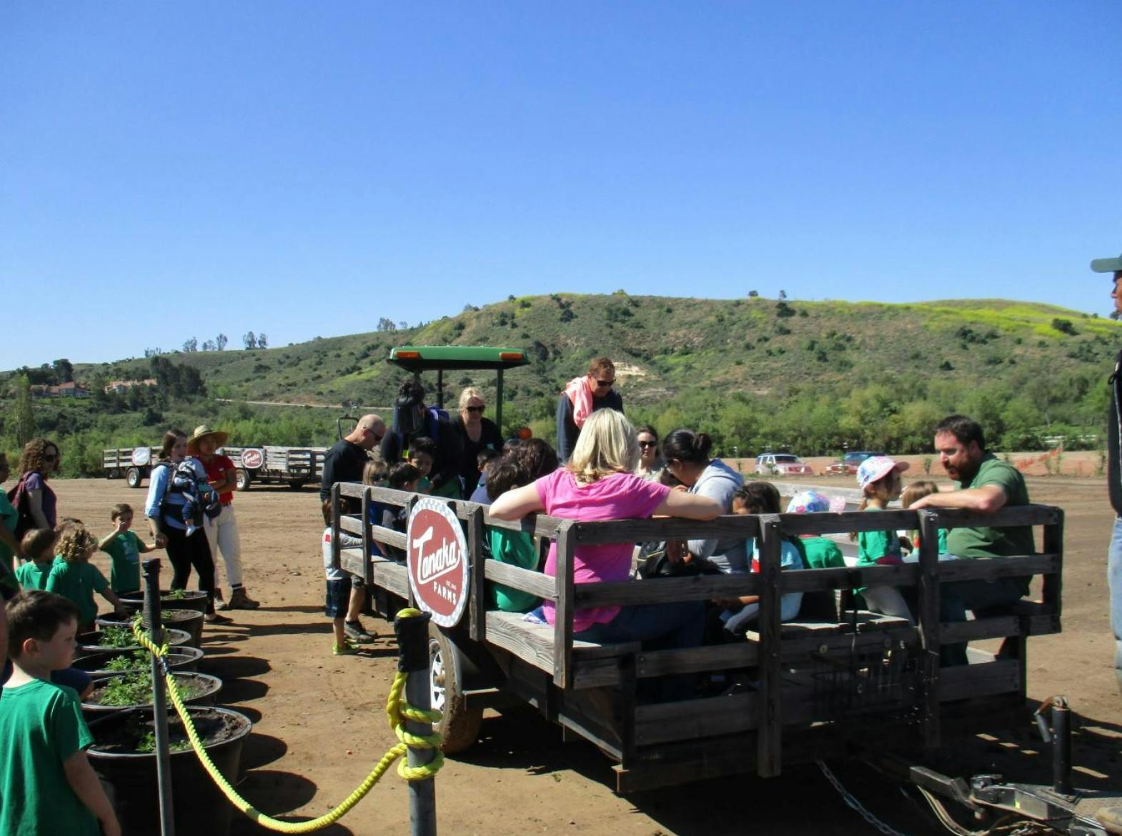 People sitting in a wagon with others standing nearby