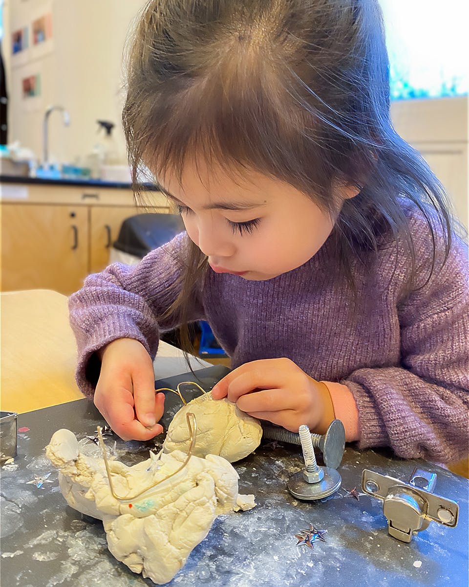Child sculpting with clay and wire