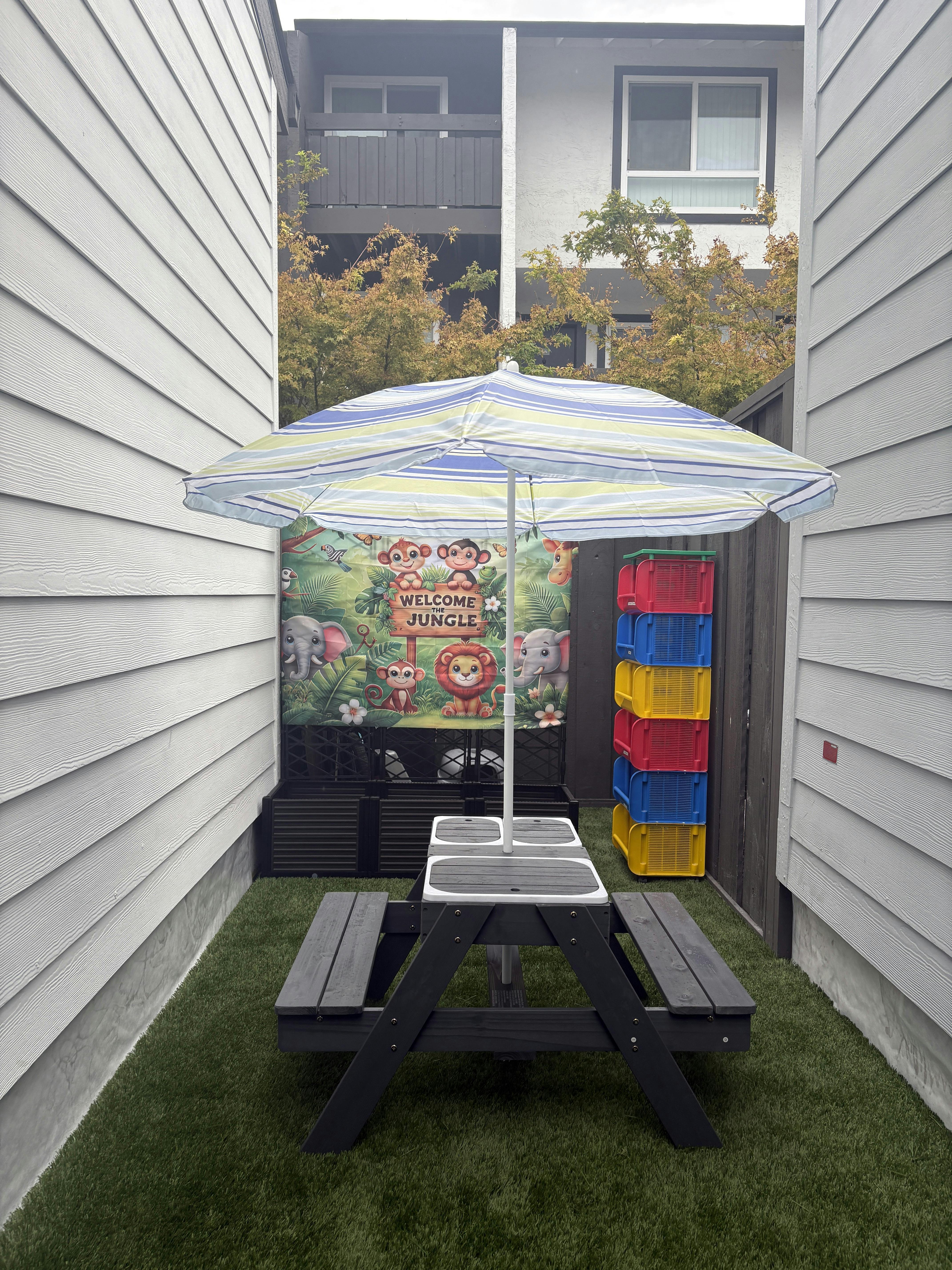 Picnic table with umbrella and "Welcome Jungle" sign