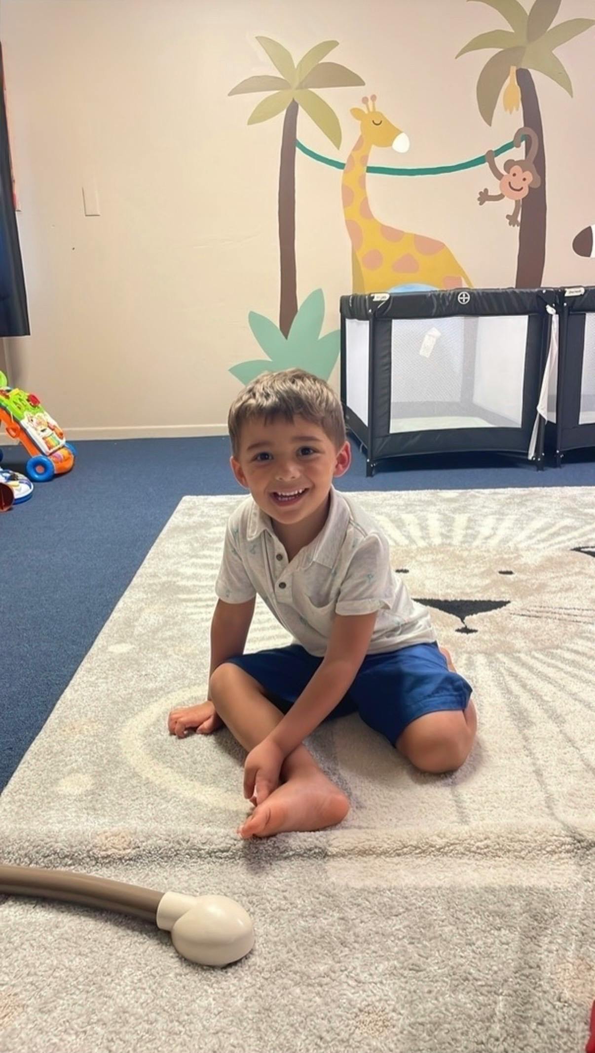 Child sitting on a floor rug in a playroom
