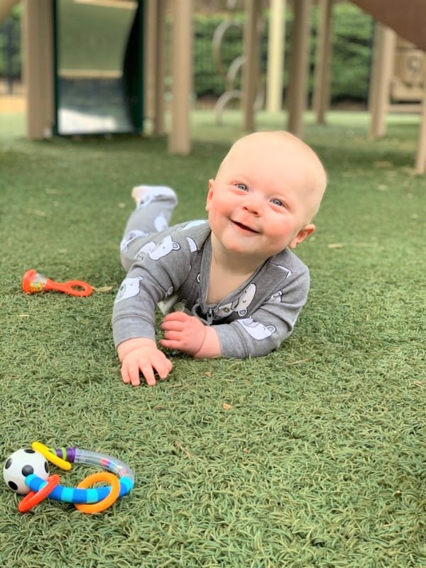 Child on stomach on artificial grass with toys