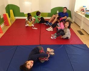 Children and adults on mats in a room