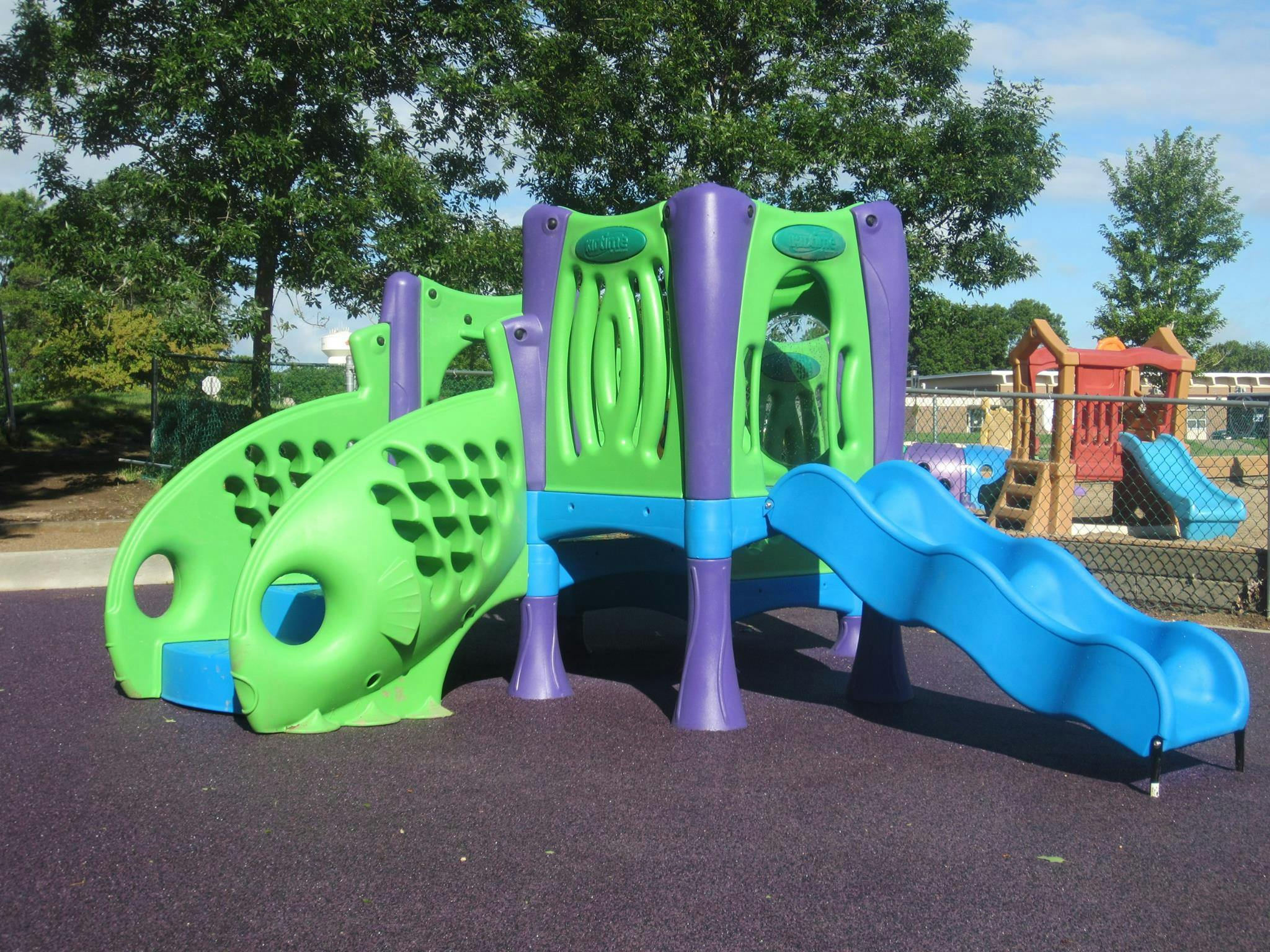 Playground structure with green, purple, and blue slides