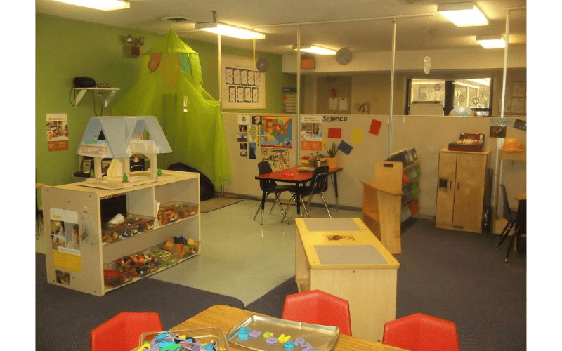 A colorful classroom with play areas, tables, and storage shelves