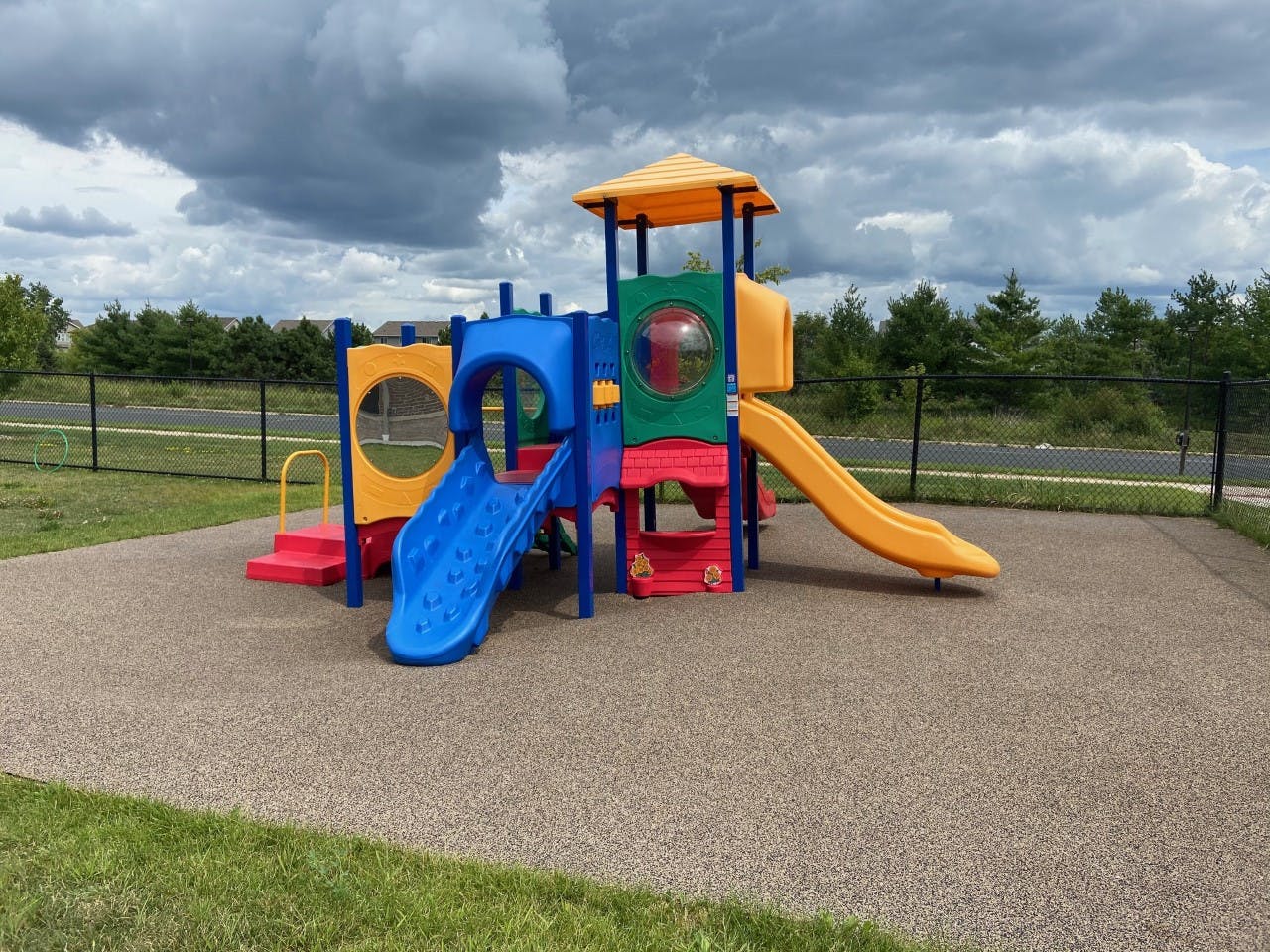 Colorful playground structure with multiple slides and climbing areas on a rubberized surface