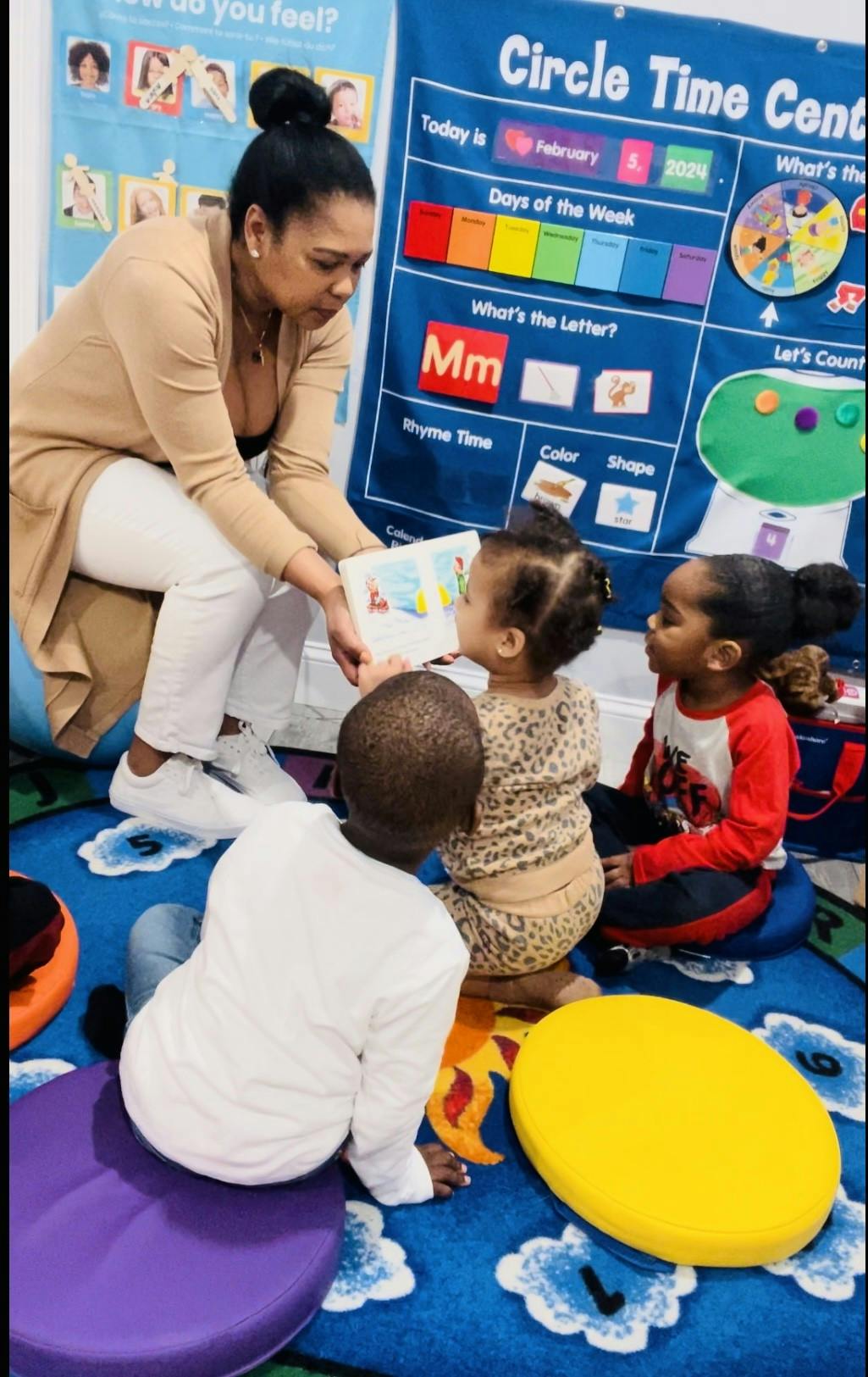 Person reading a book to three children in a classroom