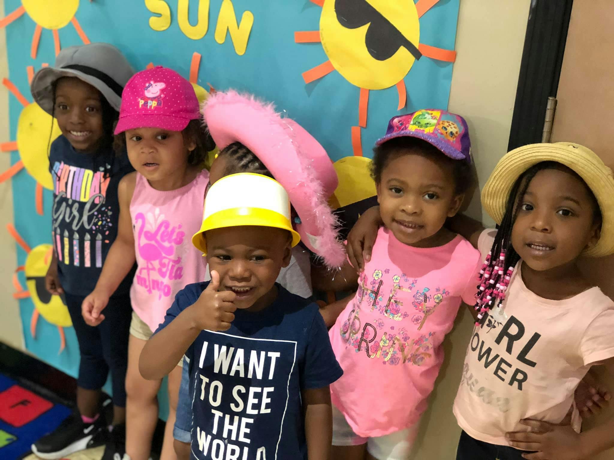 Group of children wearing hats, one child giving a thumbs up