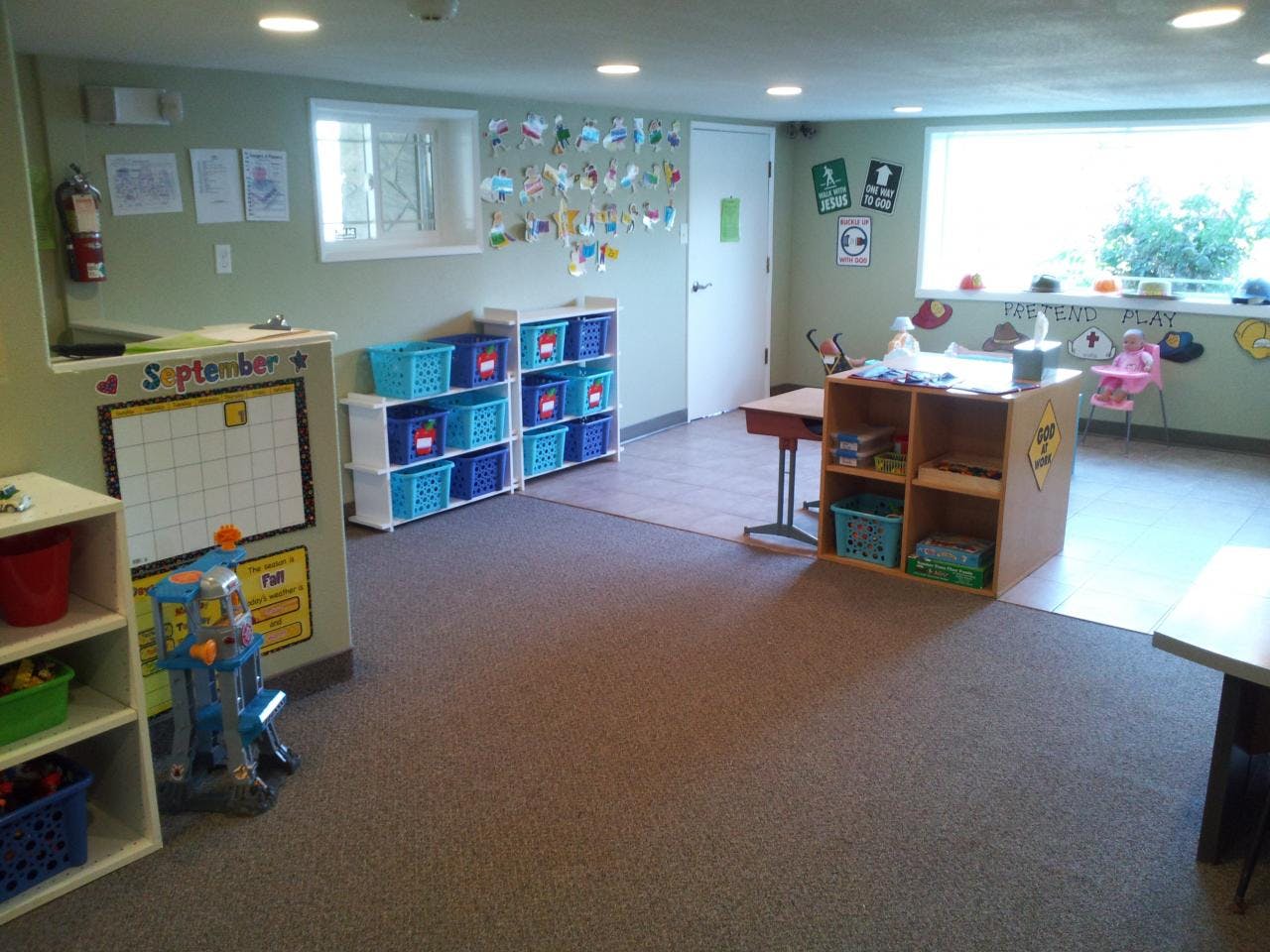Classroom with shelves of blue bins, a calendar, and a window