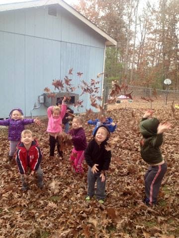 Children playing in a pile of autumn leaves