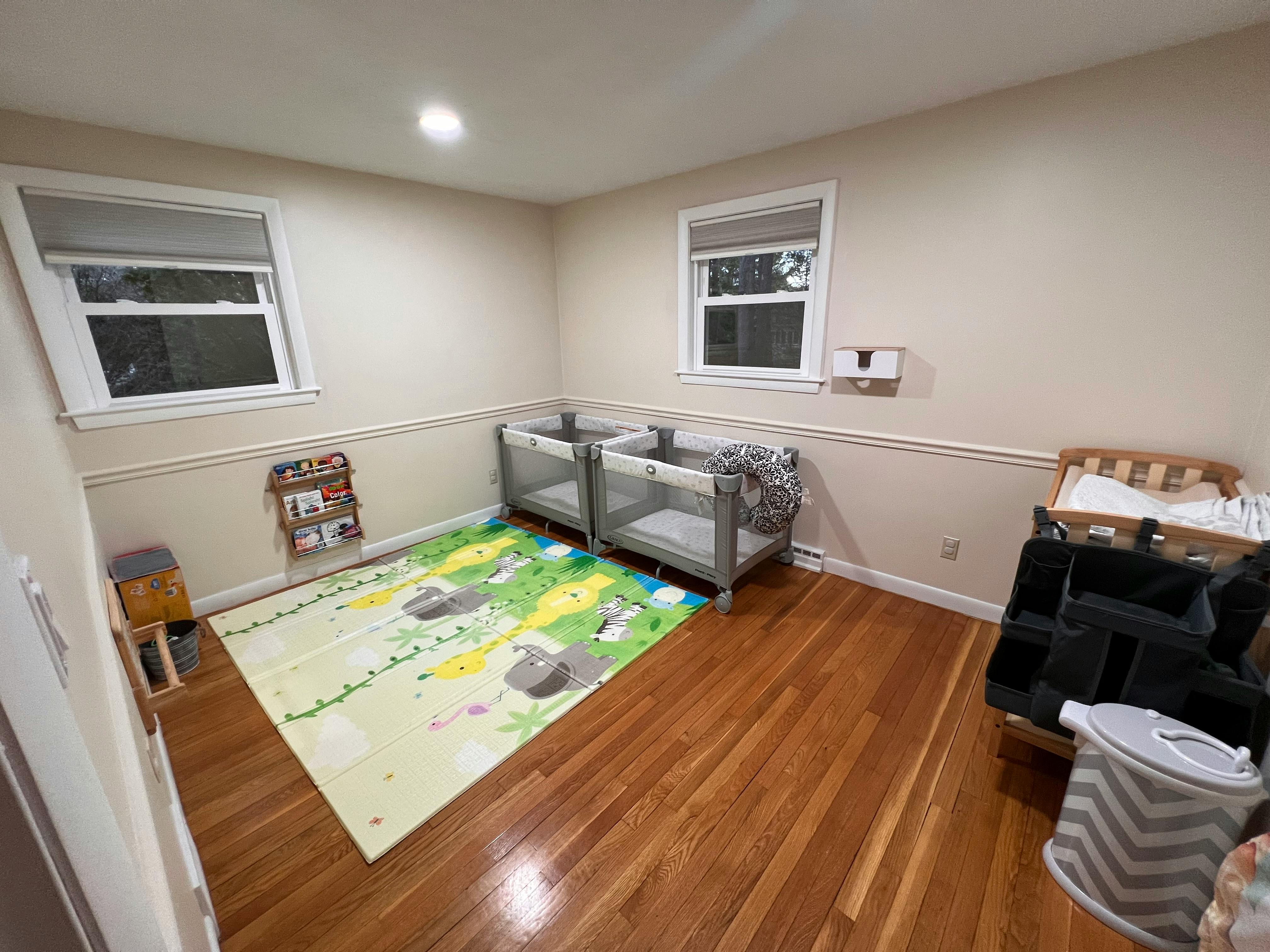 Two cribs and a playmat in a room