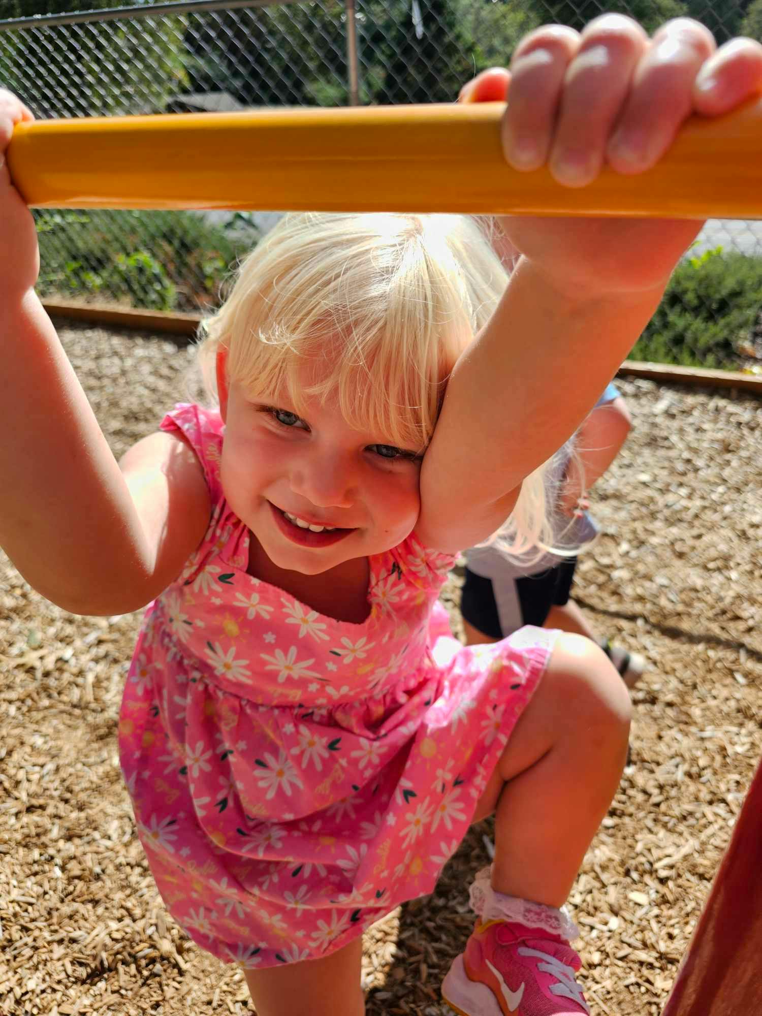 Child holding onto a yellow bar on a playground