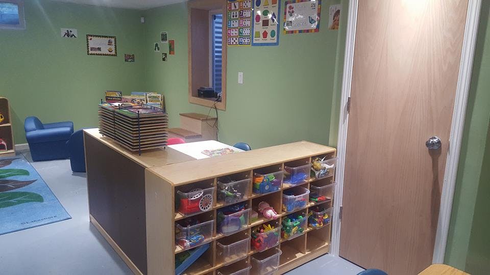 Classroom with storage unit filled with toys and a blue chair