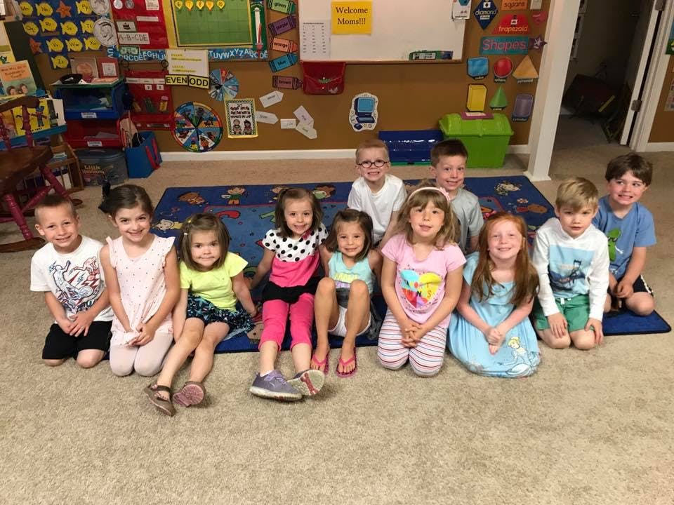 Group of children sitting on a rug in a classroom