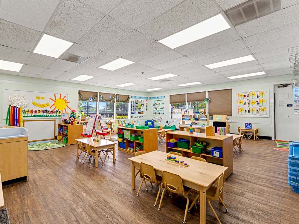 Empty children's classroom with small tables, chairs, and learning materials
