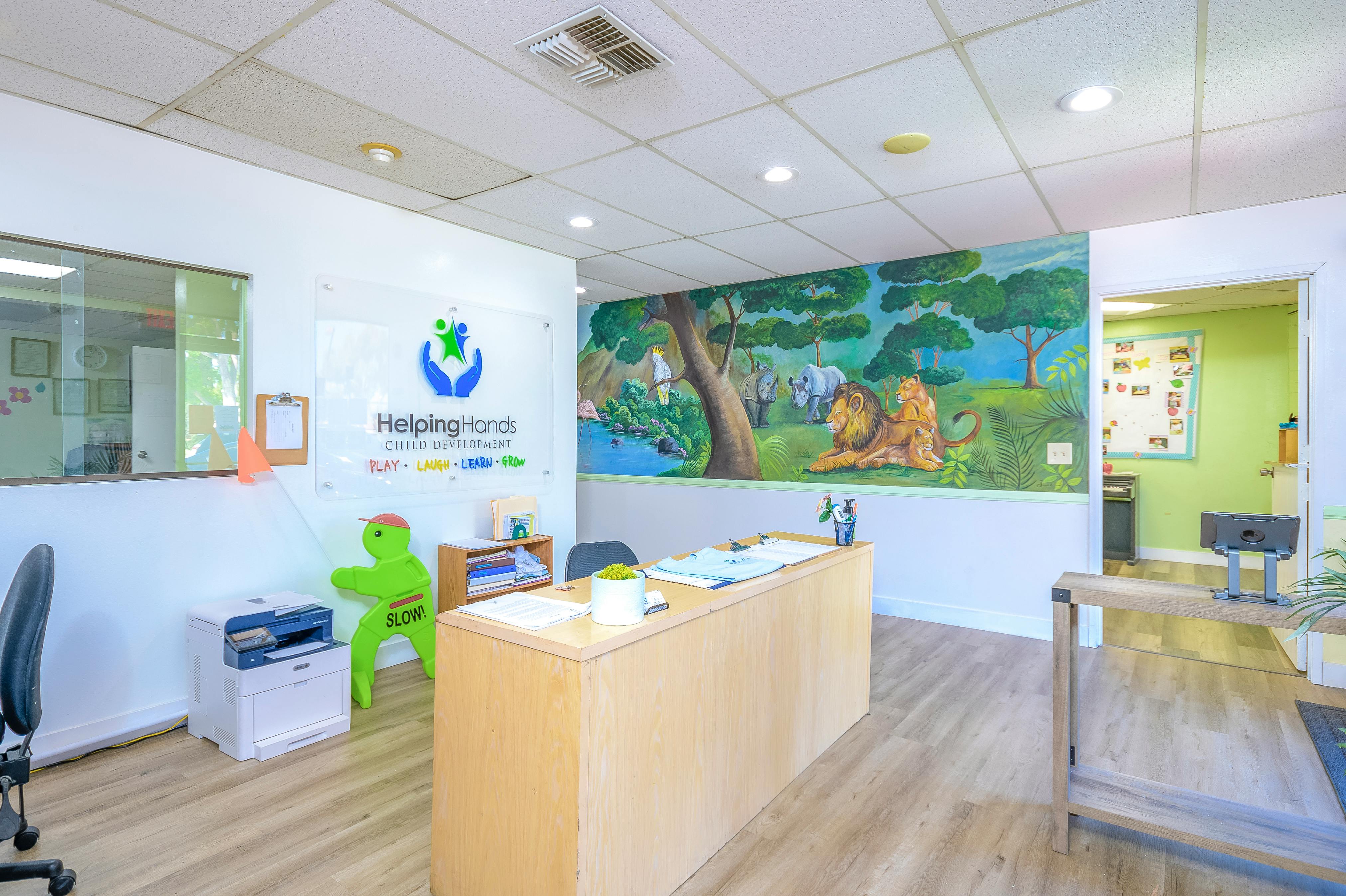 Reception area with a wooden desk and a colorful mural on the wall