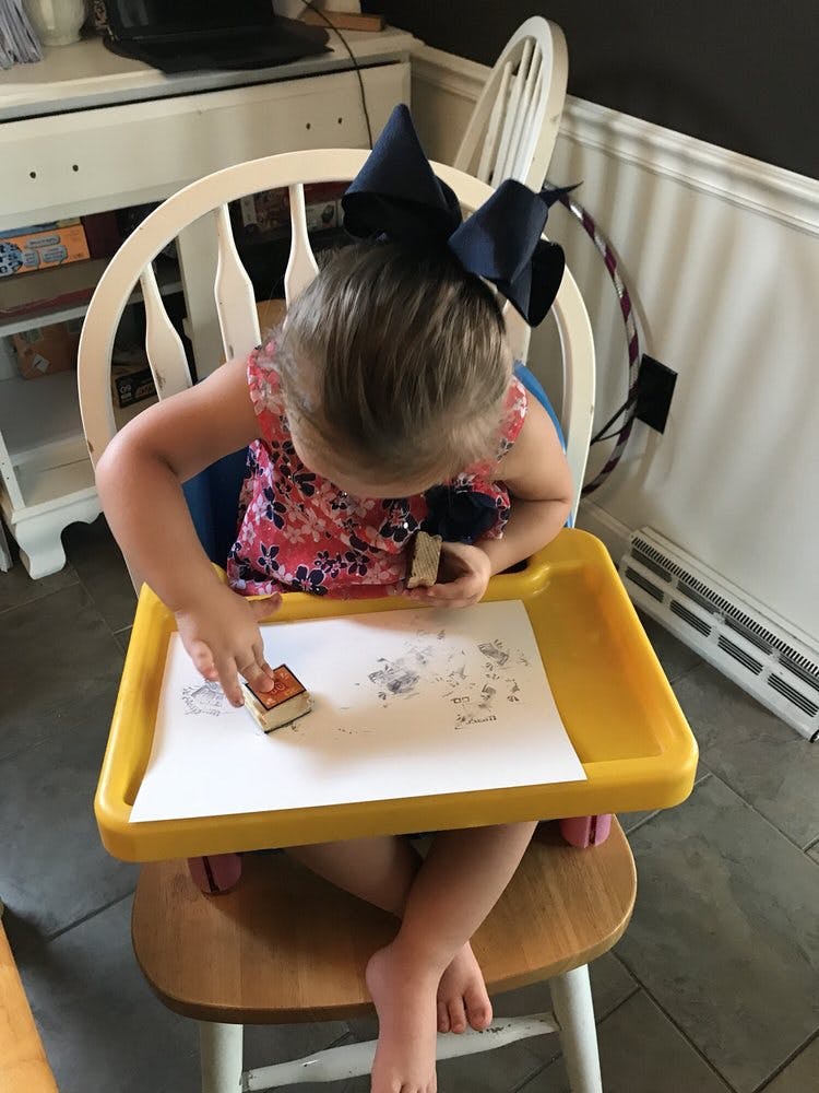 Child stamping on paper in a high chair